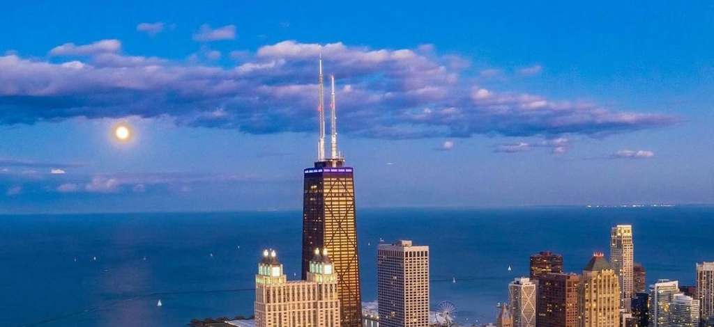 Image of the downtown Chicago skyline in the evening, as the moon rises.